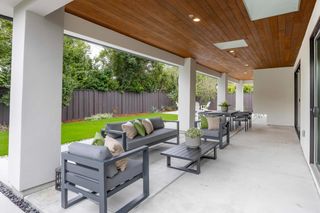 Outdoor lounge beneath a timber-lined covered terrace beside the rear lawn.